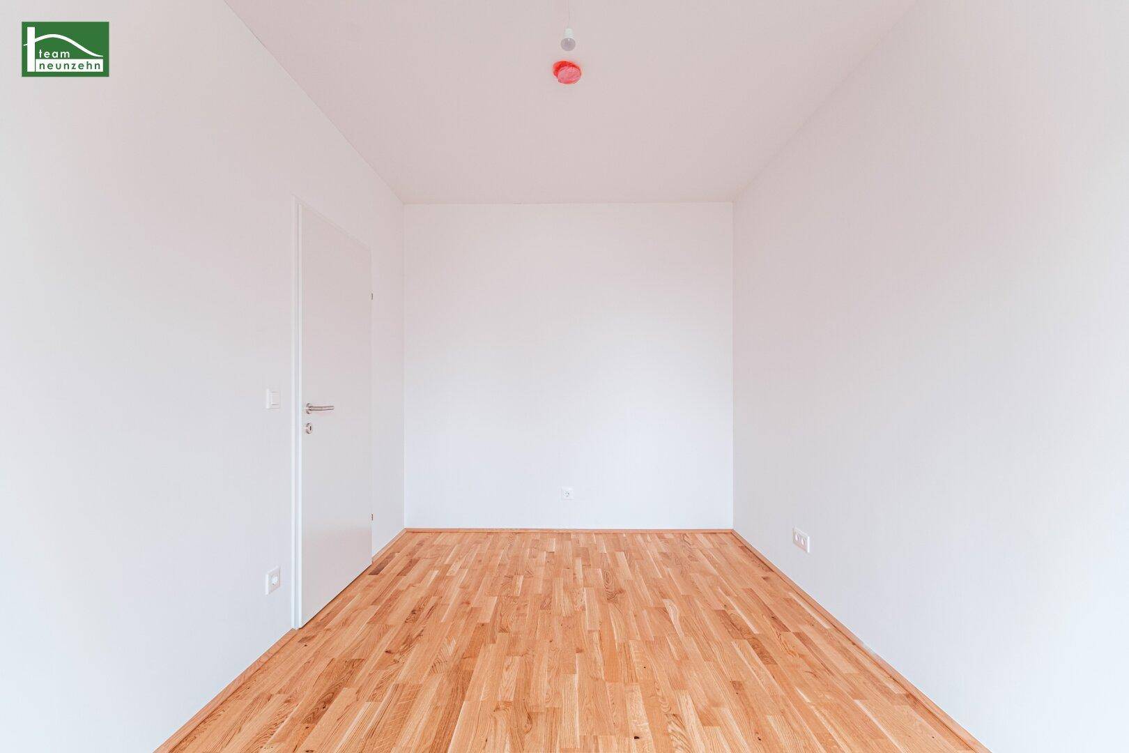 Leeres Zimmer mit hellem Parkettboden und weißen Wänden, bietet eine neutrale Basis für Einrichtung.