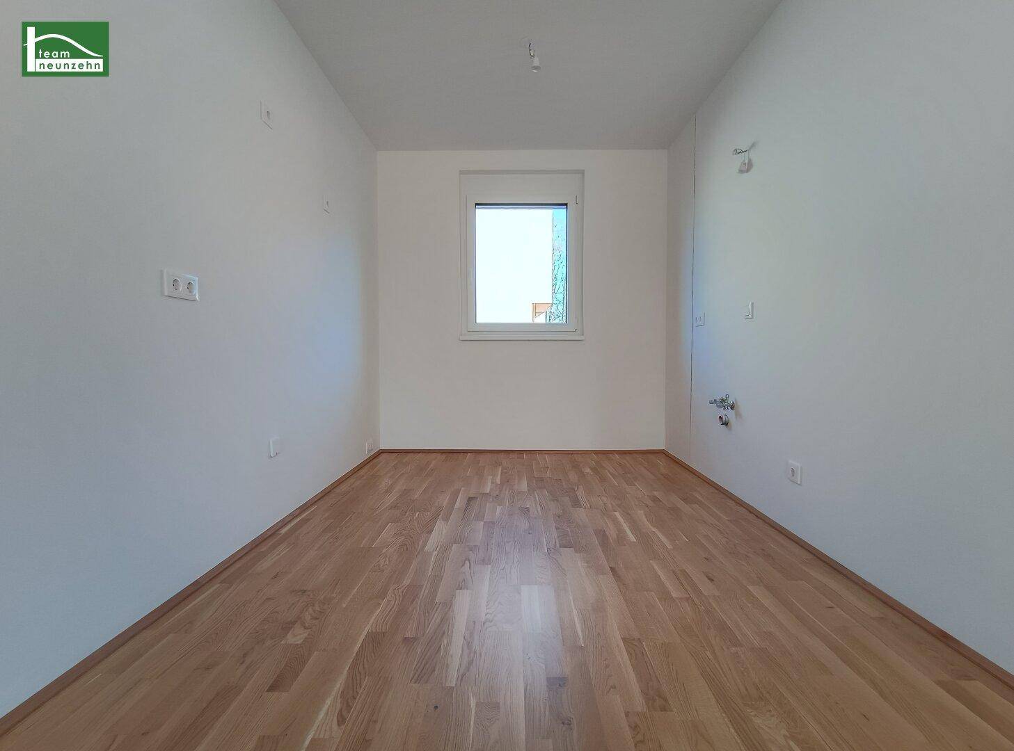 Helles, leeres Zimmer mit Parkettboden und einem Fenster, ideal als Schlaf- oder Arbeitszimmer.