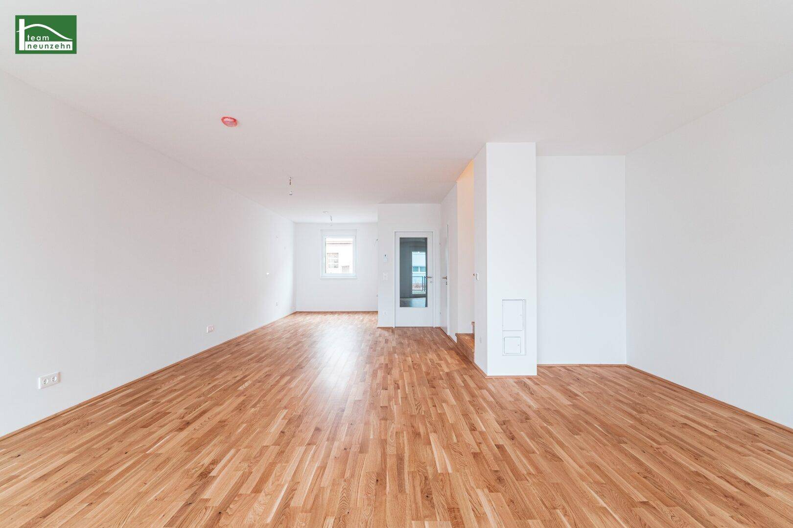 Lichtdurchfluteter Wohnbereich mit hellem Parkettboden und moderner, minimalistischer Gestaltung.
