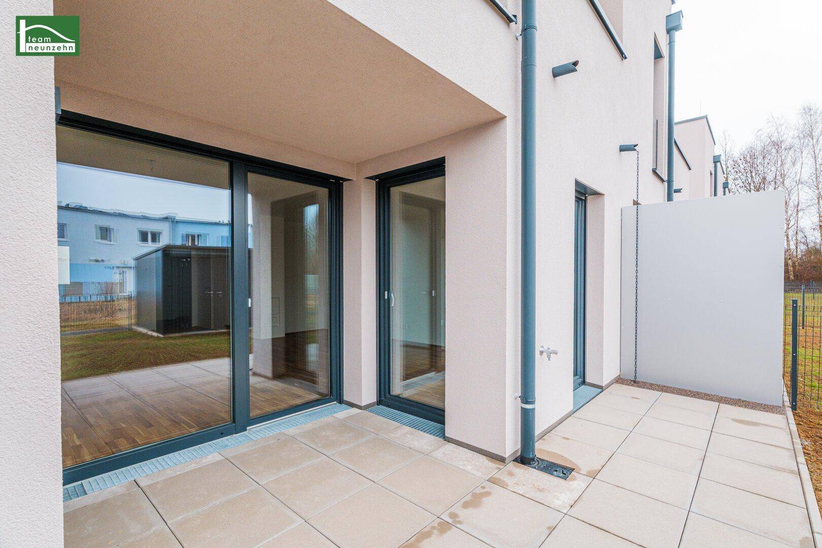 Geflieste Terrasse im Erdgeschoss mit Zugang zum Garten und großen Schiebetüren.