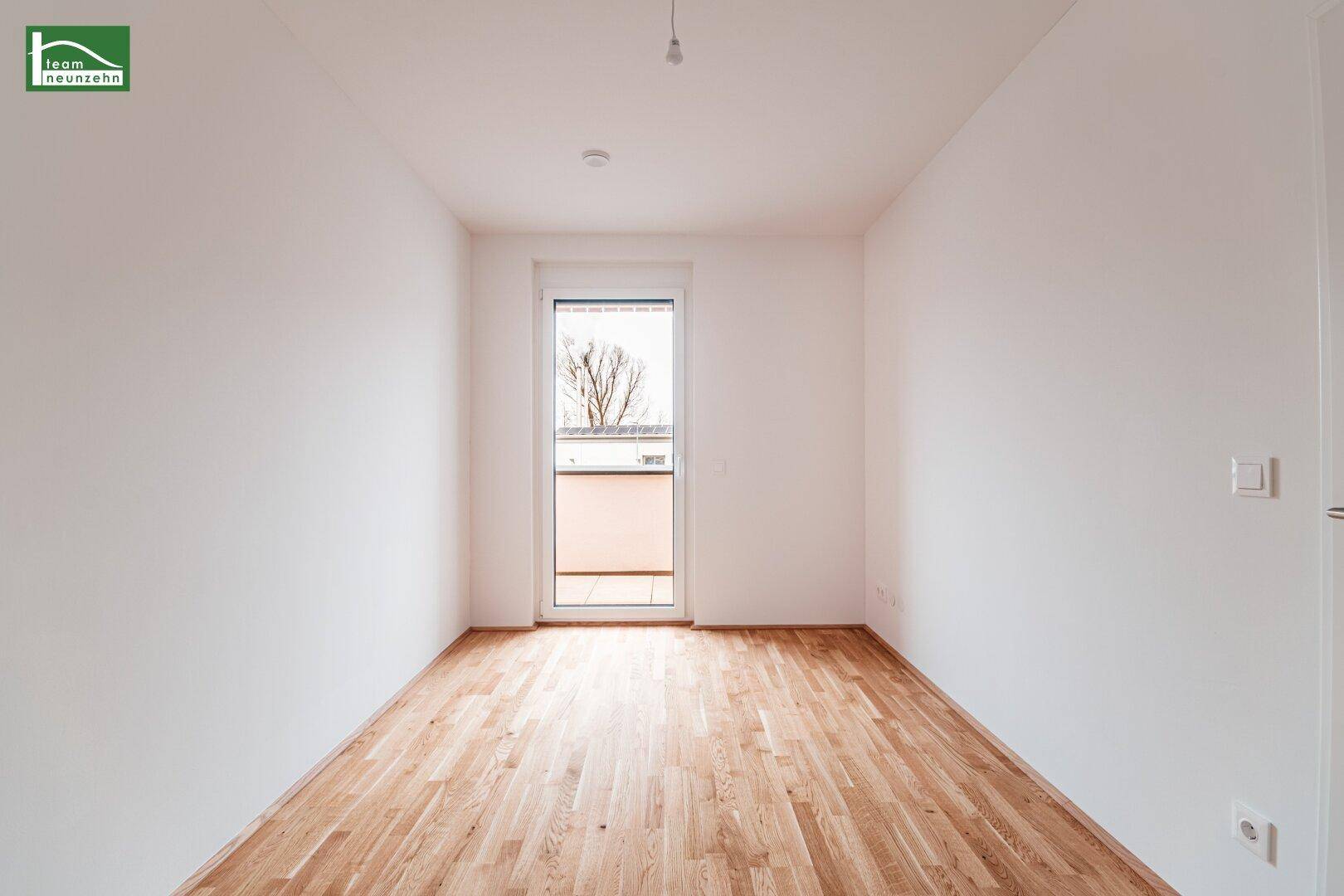Helles Zimmer mit Parkettboden und Zugang zu einem kleinen Balkon, ideal als Schlaf- oder Gästezimmer.