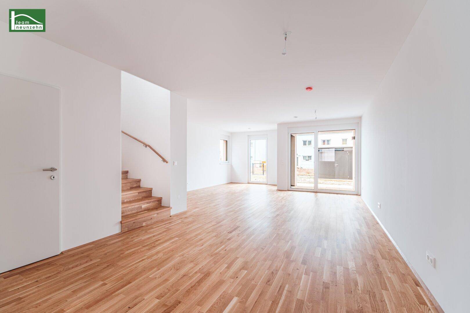 Heller Wohnbereich mit Holztreppe und Zugang zur Terrasse, ideal für offenes Wohnen.