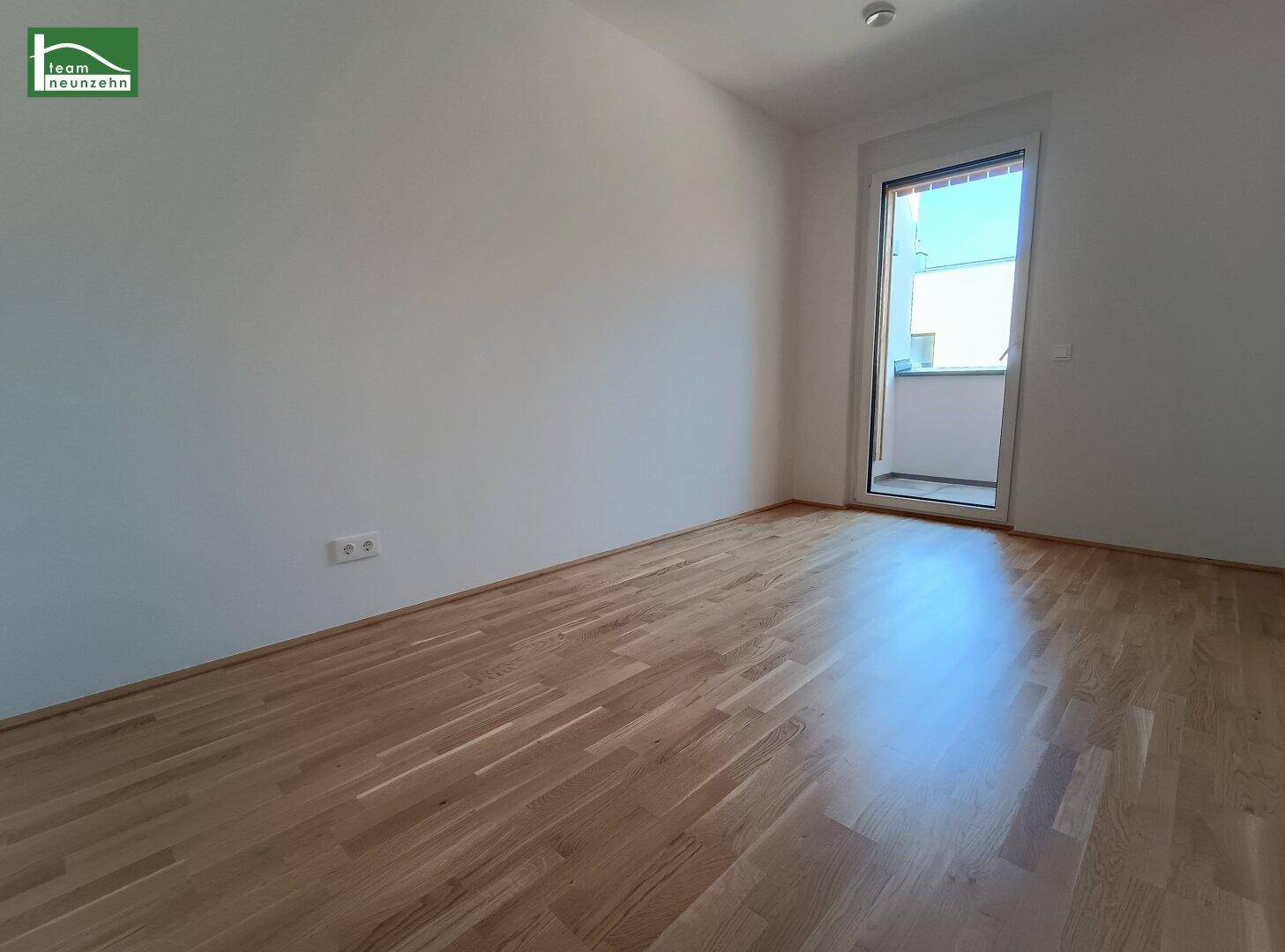Lichtdurchflutetes Zimmer mit Holzboden und Balkonzugang, perfekt für ein Schlafzimmer oder Büro.