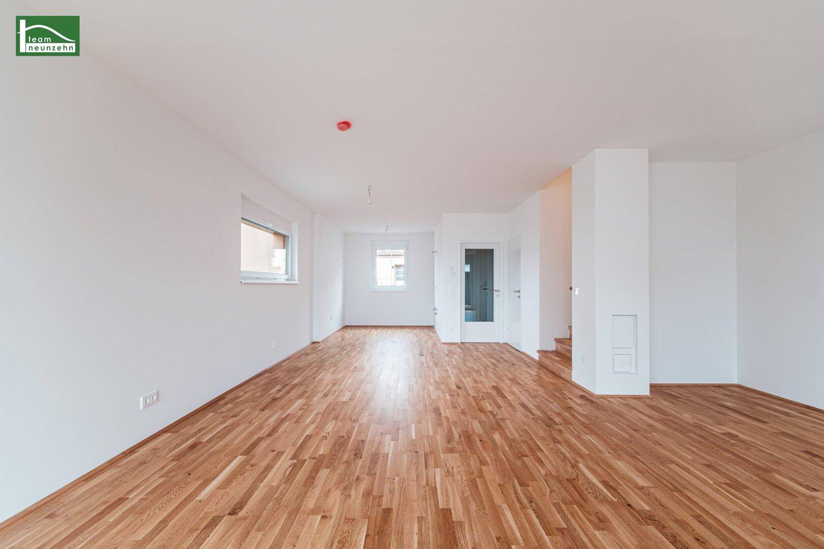 Heller Wohnbereich mit Holzparkett und Treppe zum Obergeschoss, bereit zur individuellen Gestaltung.