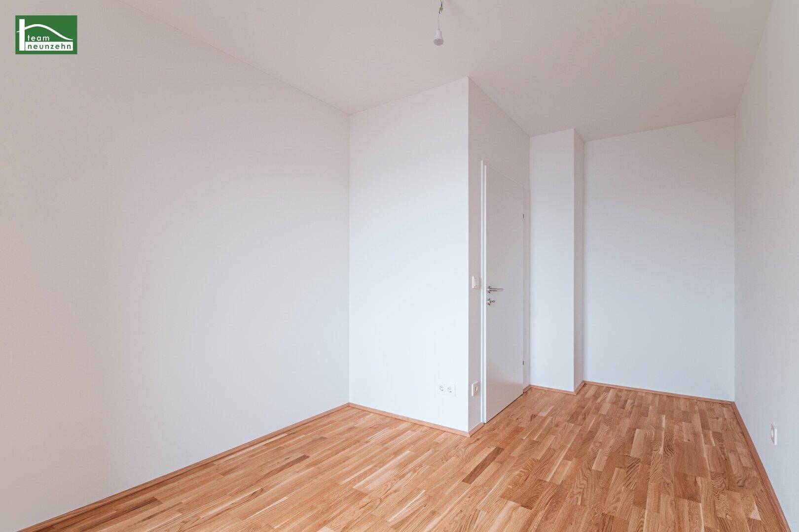 Leerer Raum mit Holzparkettboden und weißen Wänden, ideal als Schlaf- oder Arbeitszimmer.