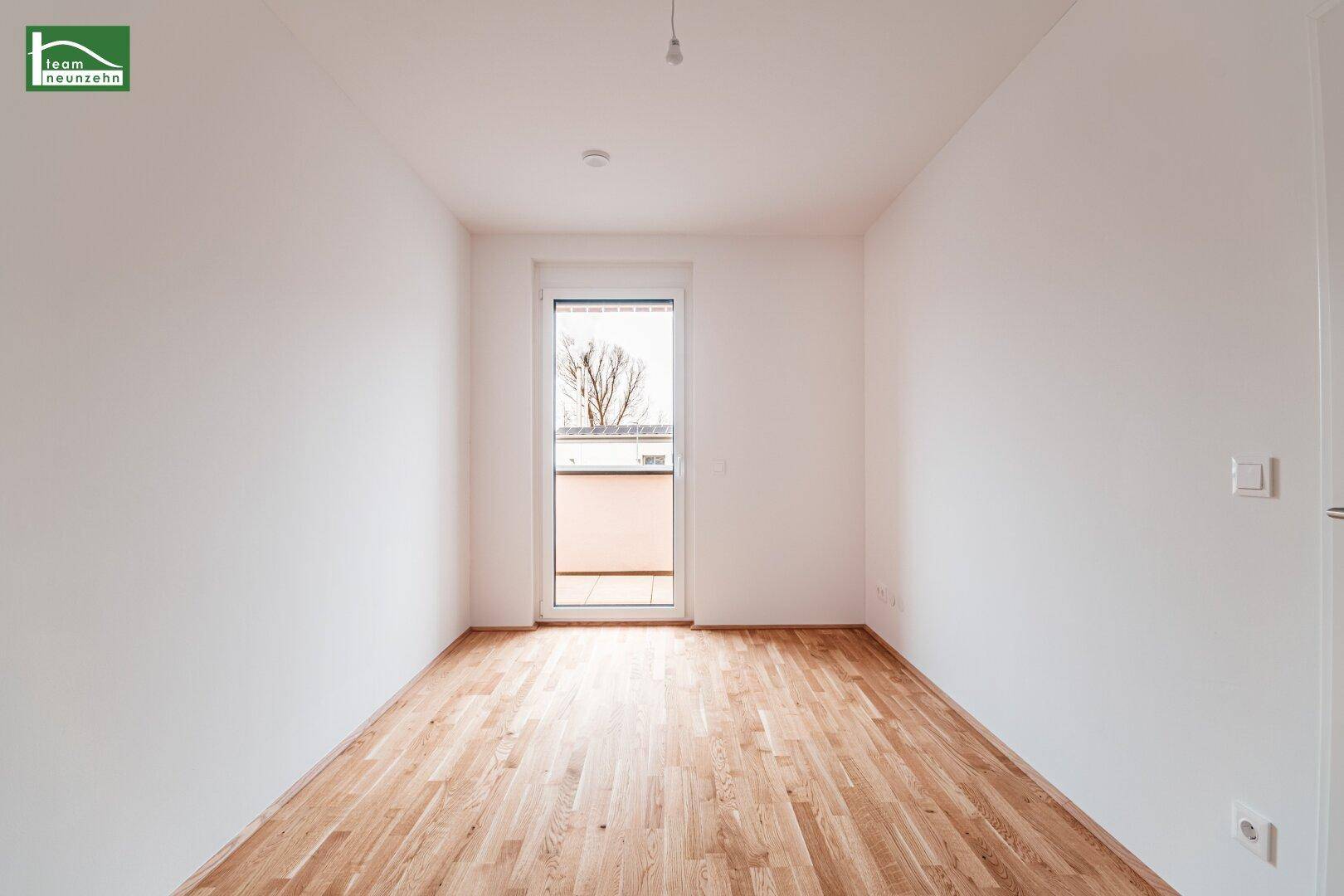 Helles Schlafzimmer mit Holzboden und Zugang zu einem kleinen Balkon.