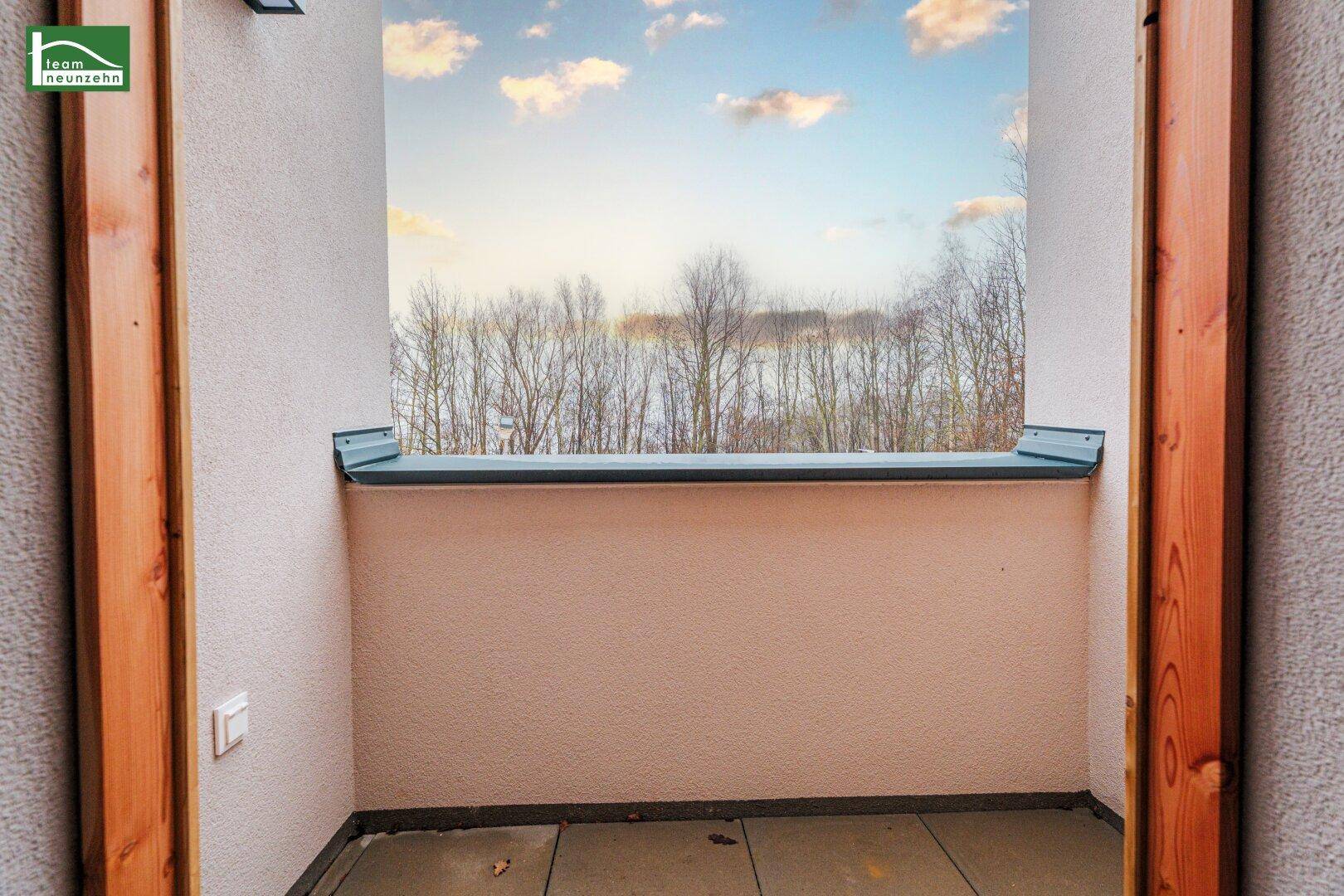 Kleiner, gefliester Balkon mit Blick auf Bäume und den weiten Himmel.