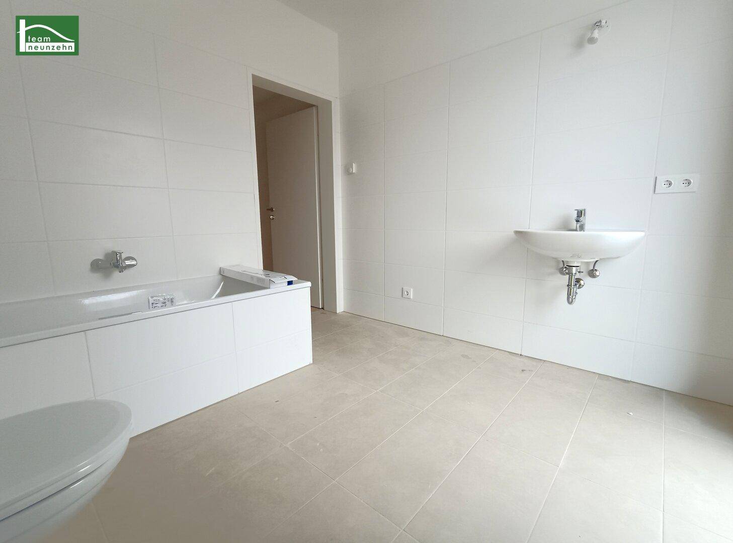 Geräumiges Badezimmer mit Badewanne, Waschbecken und hellen Fliesen.