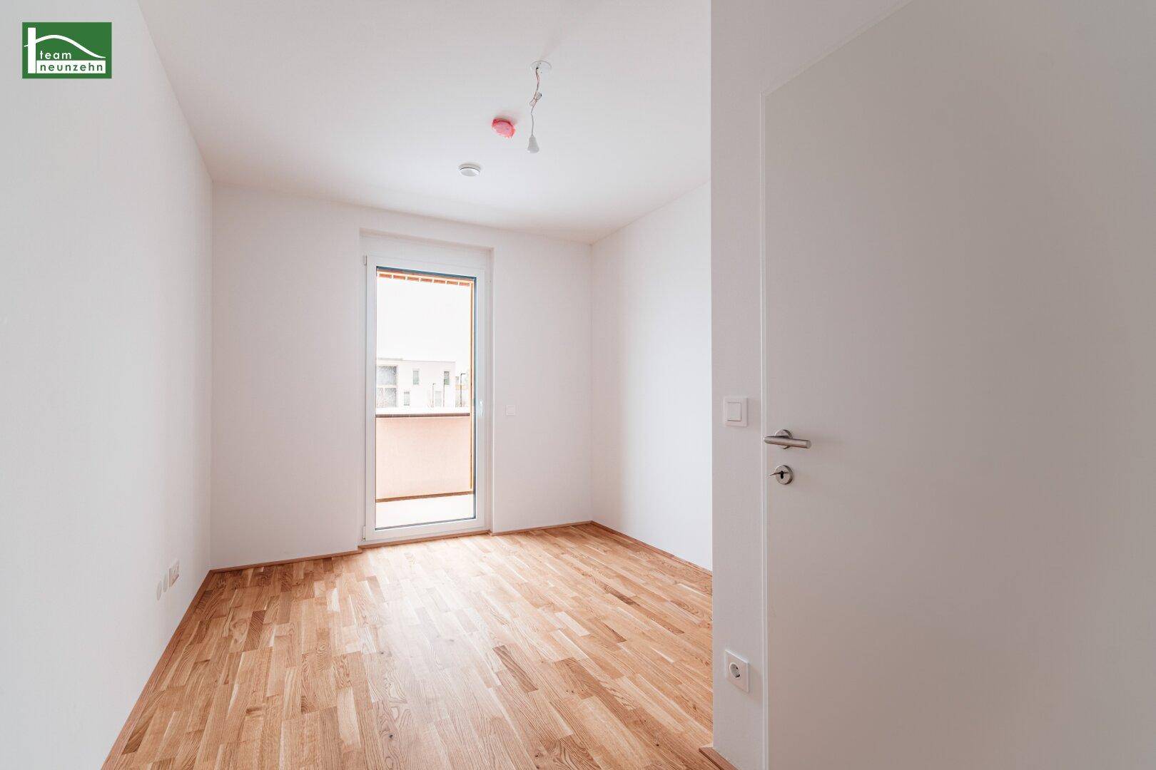 Helles Schlafzimmer mit Parkettboden und Zugang zu einem französischen Balkon oder kleiner Terrasse.