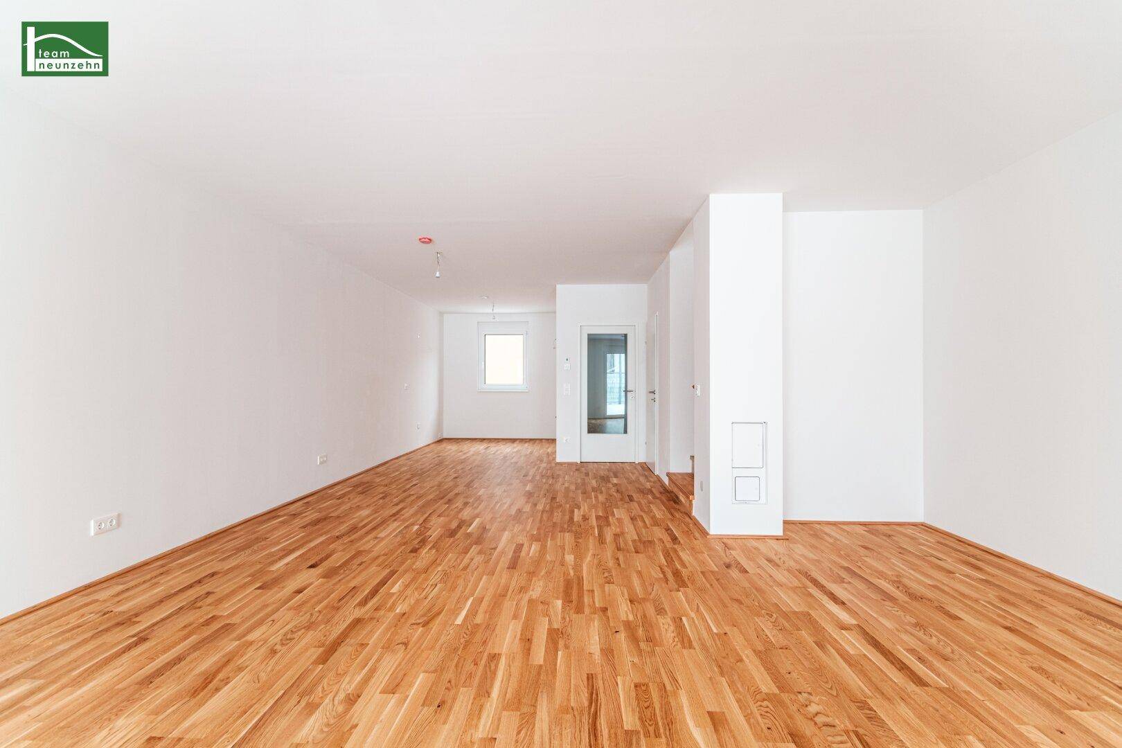 Weitläufiger Wohnbereich mit hellem Parkettboden und viel Tageslicht, ideal für offenes Wohnen.