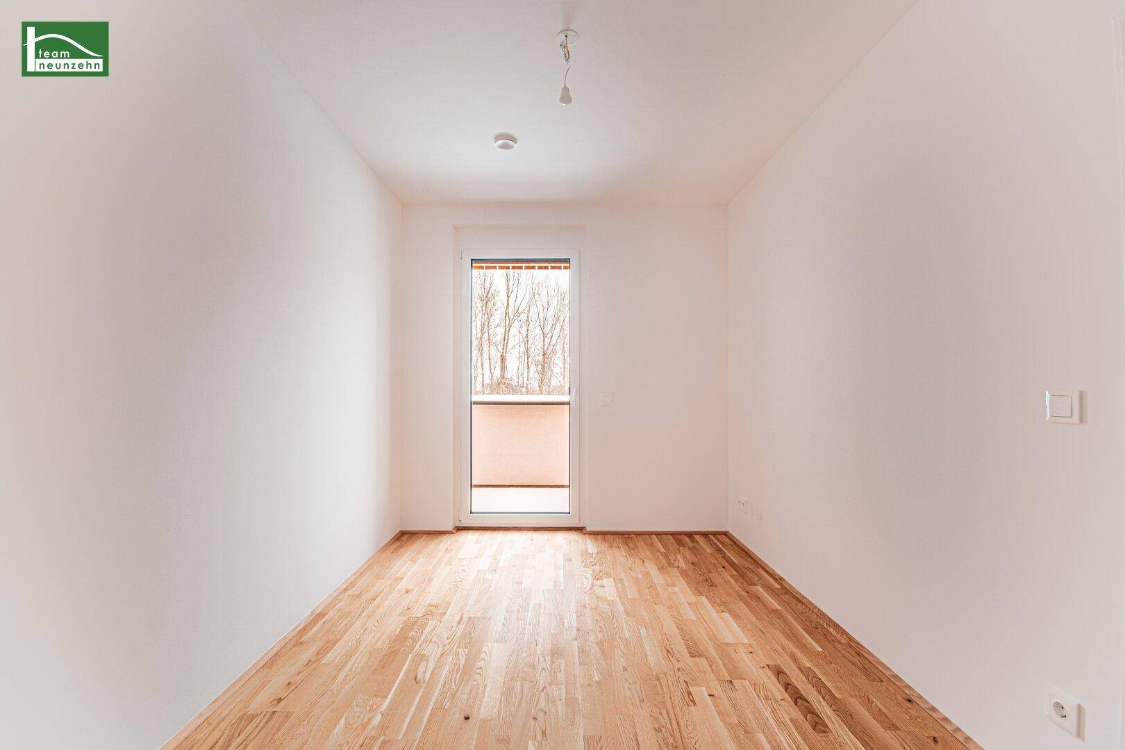 Helles Schlafzimmer mit Parkettboden und Zugang zu einem Außenbereich, ideal für frische Luft.