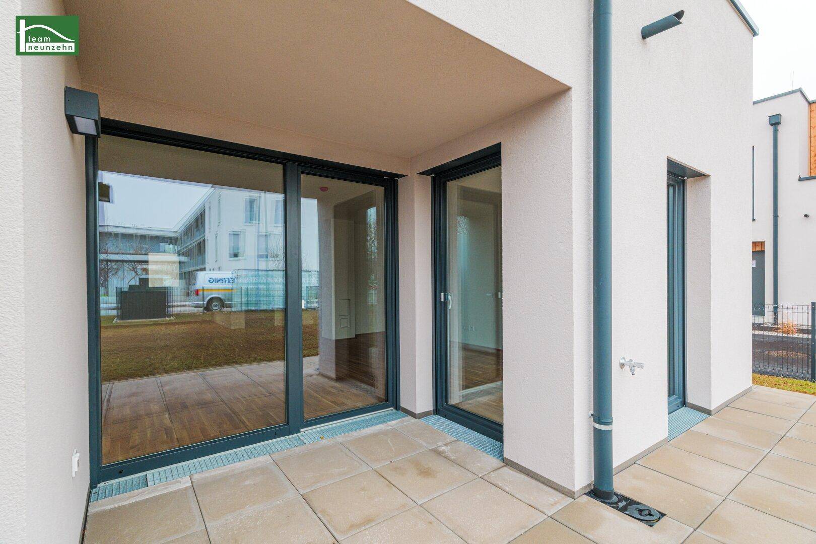 Geräumige Terrasse mit Fliesenboden und großzügigen Glasfronten zum Wohnbereich.