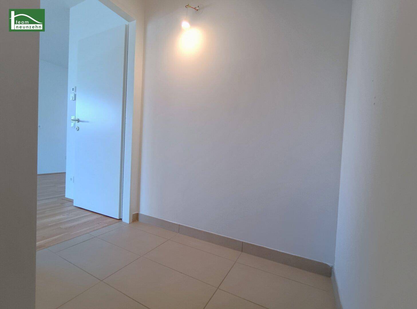 Heller Flur mit Fliesenboden und weißer Tür, führt zu den weiteren Räumen der Wohnung.