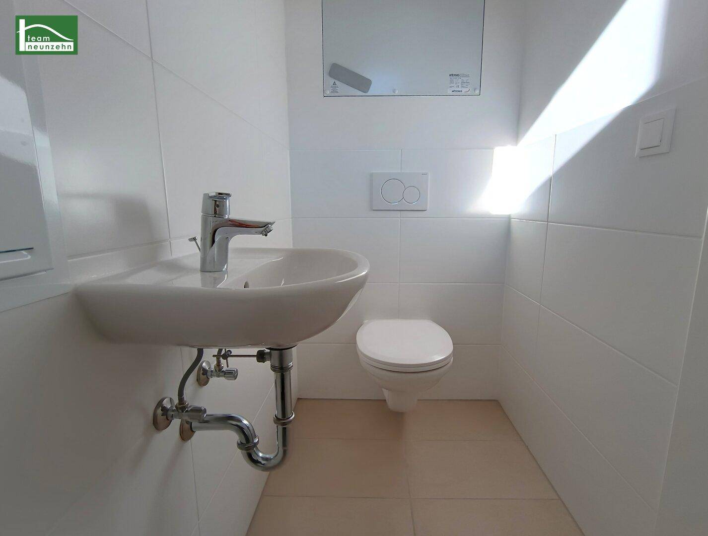 Modernes Gäste-WC mit Waschbecken und wandhängendem WC, in schlichtem Design gehalten.