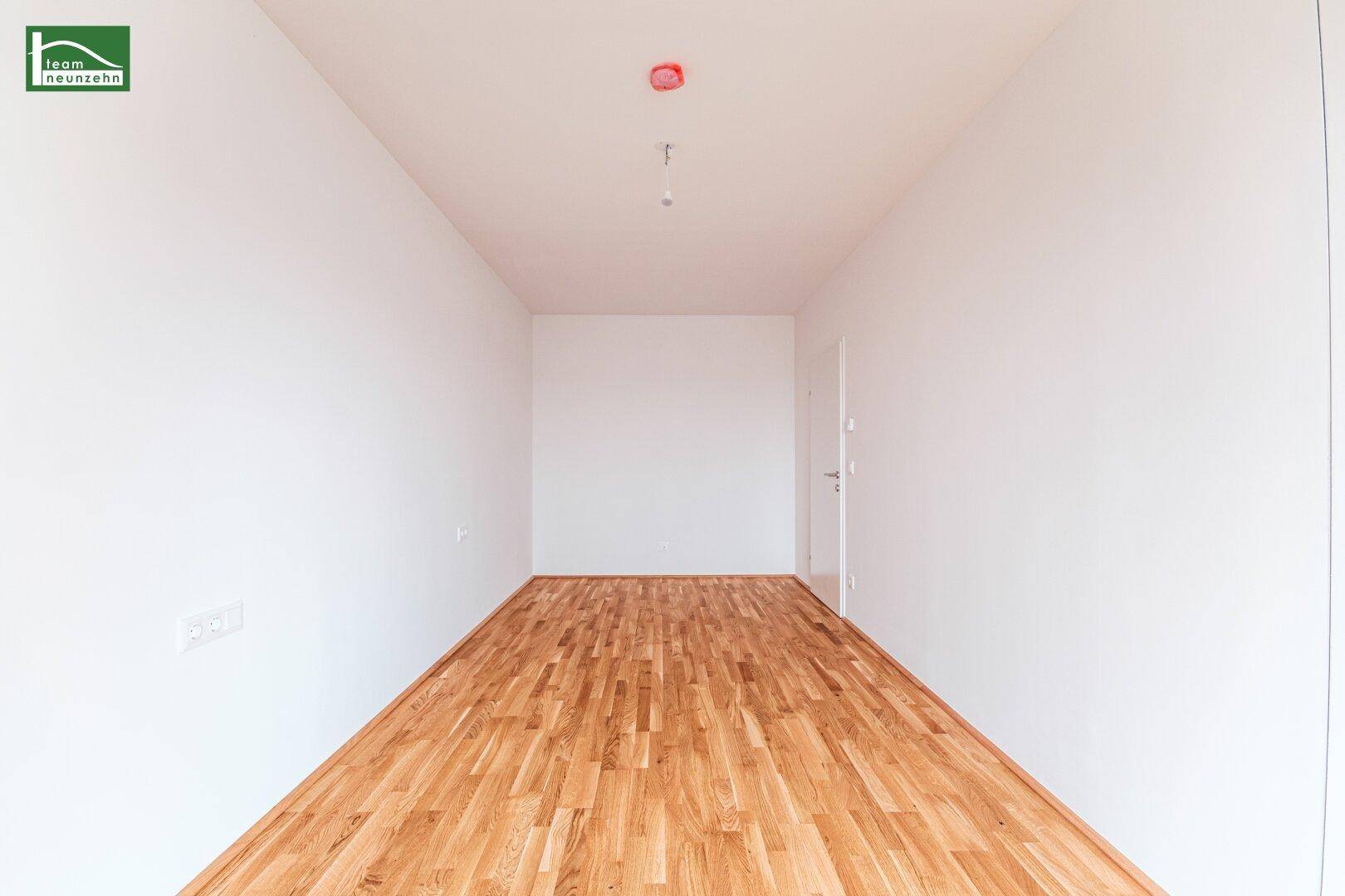 Leeres Zimmer mit Parkettboden und weiß gestrichenen Wänden, bereit zur individuellen Gestaltung.