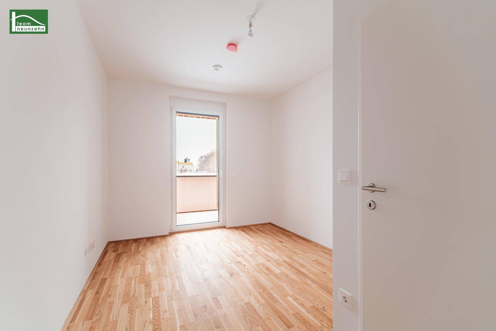 Helles Schlafzimmer mit Parkettboden und Zugang zum Balkon, bietet viel natürliches Licht.