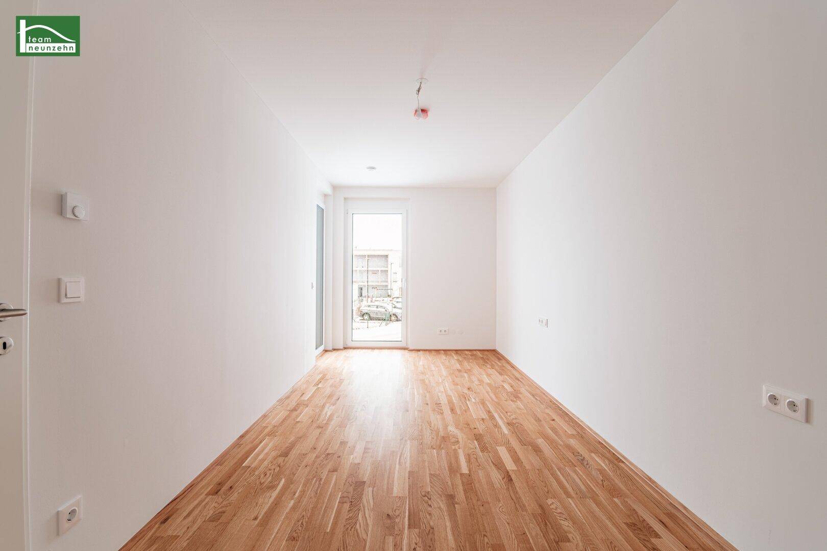 Helles Zimmer mit Parkettboden und Zugang zu einem Balkon, ideal als Schlaf- oder Arbeitszimmer.