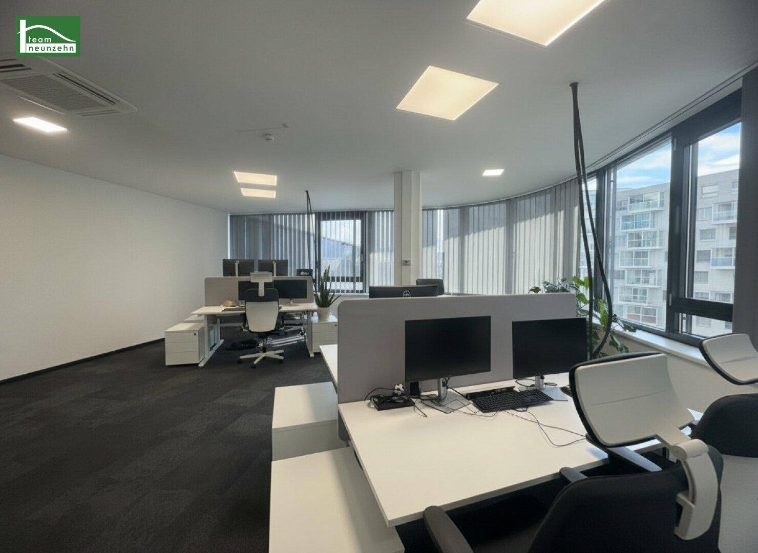 Moderner Bürobereich mit flexiblen Arbeitsplätzen, Trennwänden und viel Tageslicht.