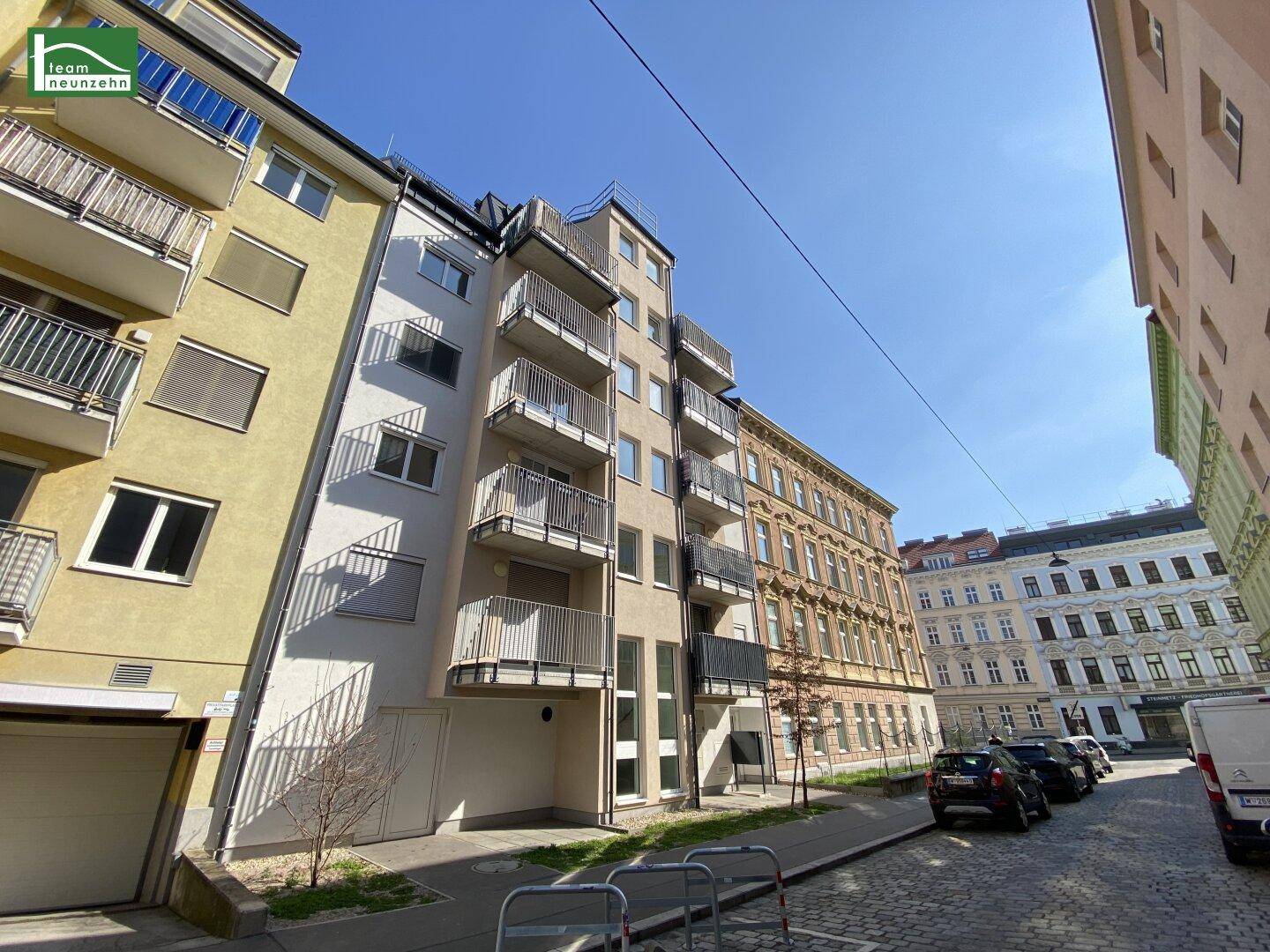 Moderne Wohngebäude mit Balkonen und traditionellen Altbauten in einer städtischen Umgebung.