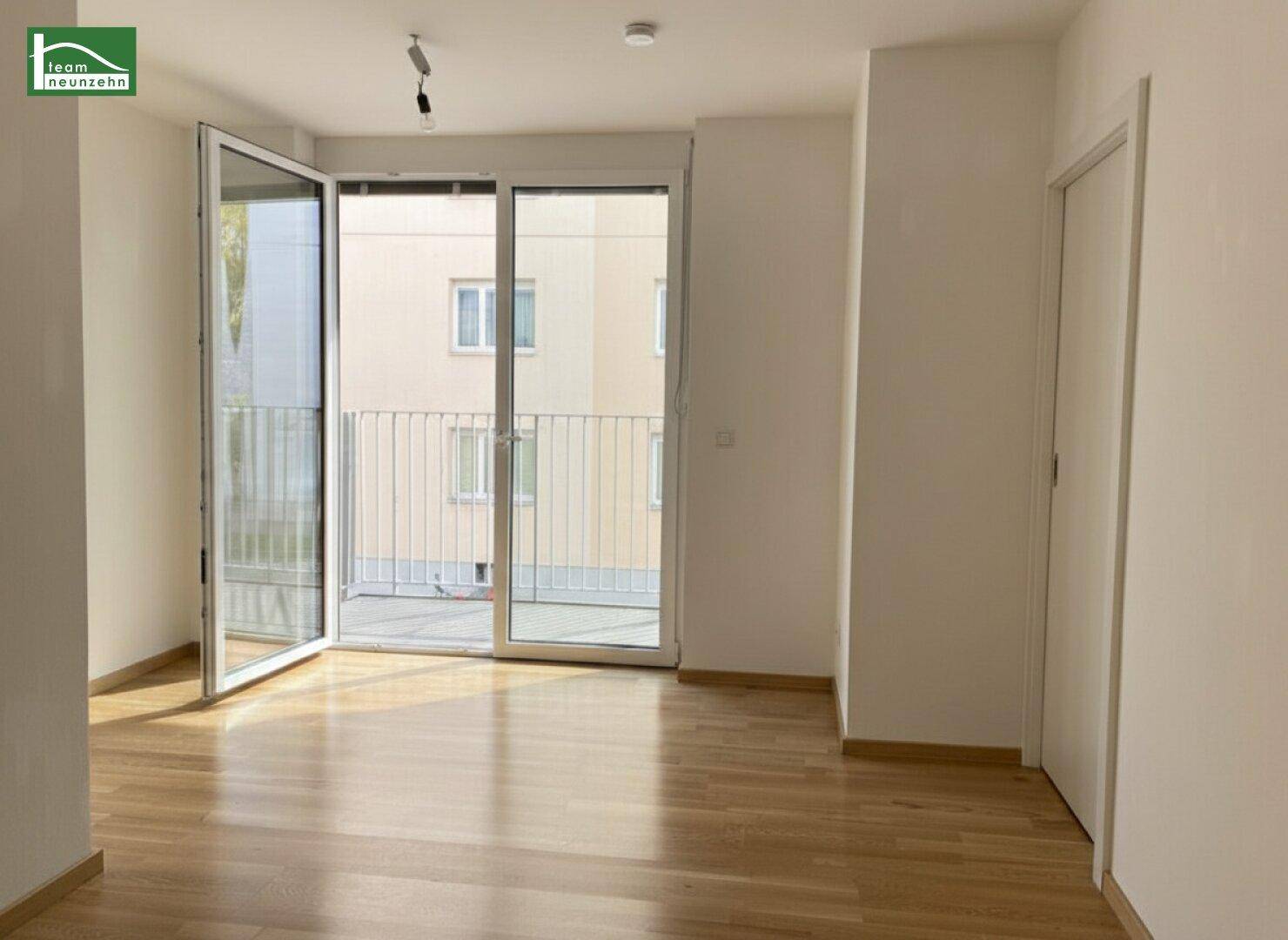 Lichtdurchfluteter Wohnbereich mit Holzboden und großen Fenstern, die viel Tageslicht hereinlassen.