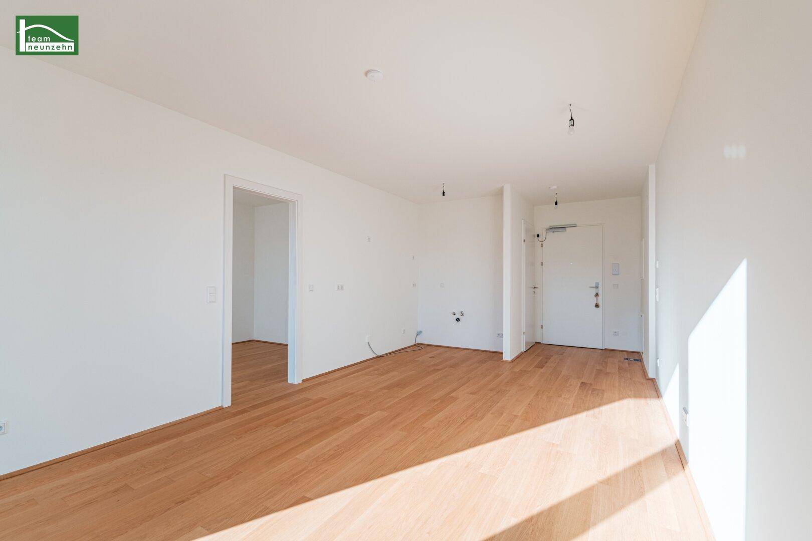 Heller Eingangsbereich mit Holzboden und offener Verbindung zu weiteren Räumen.