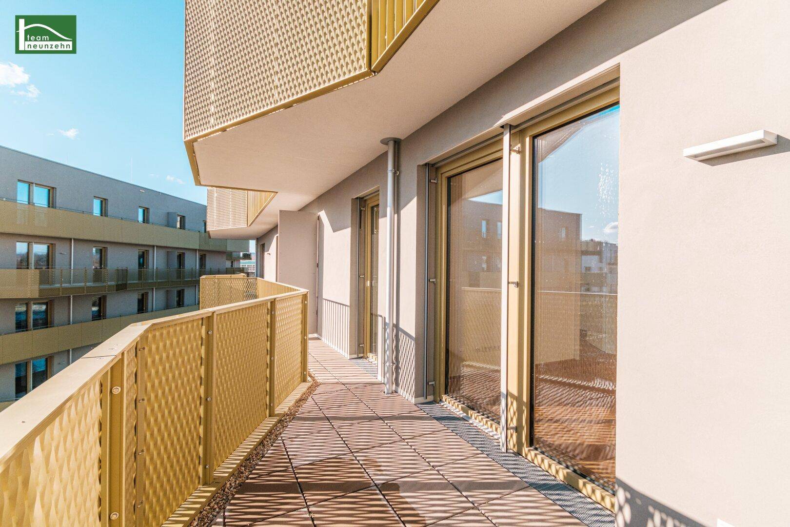 Langer Balkon mit modernem Lochblechgeländer und Fliesenboden, sonnig gelegen.