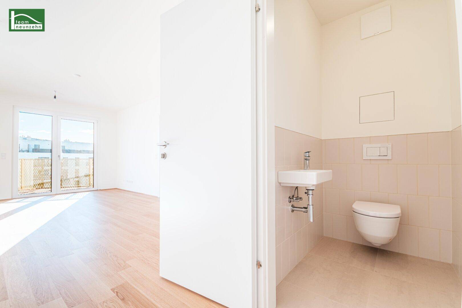 Separates Gäste-WC mit wandhängendem WC und kleinem Waschbecken, hell gefliest.