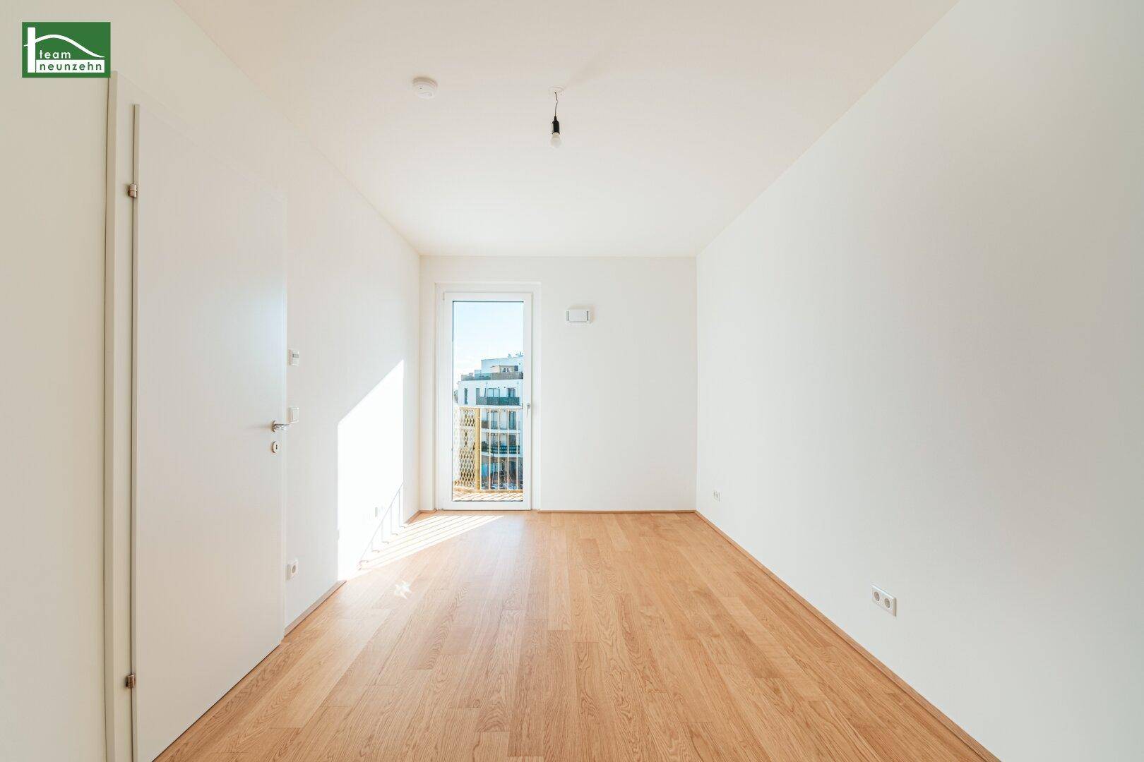 Heller, leerer Raum mit Holzboden und Zugang zu einem Balkon, ideal für Wohn- oder Schlafzimmer.