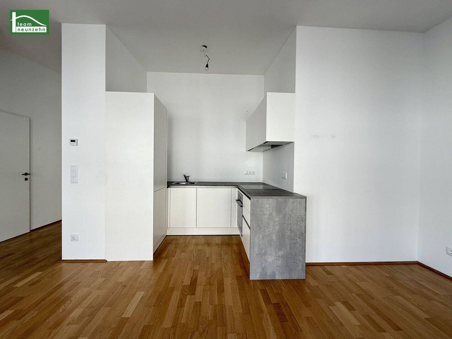 Moderne Küchenzeile mit weißen Schränken, integriertem Backofen und Dunstabzugshaube.