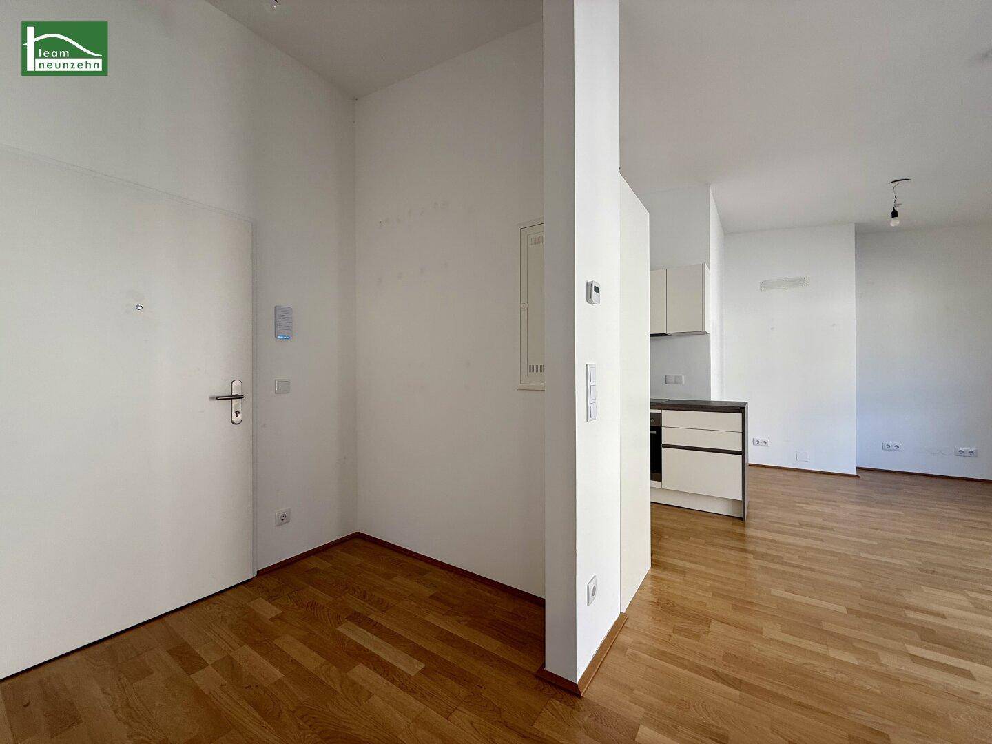 Eingangsbereich mit Holzboden, der in den offenen Wohnbereich übergeht.