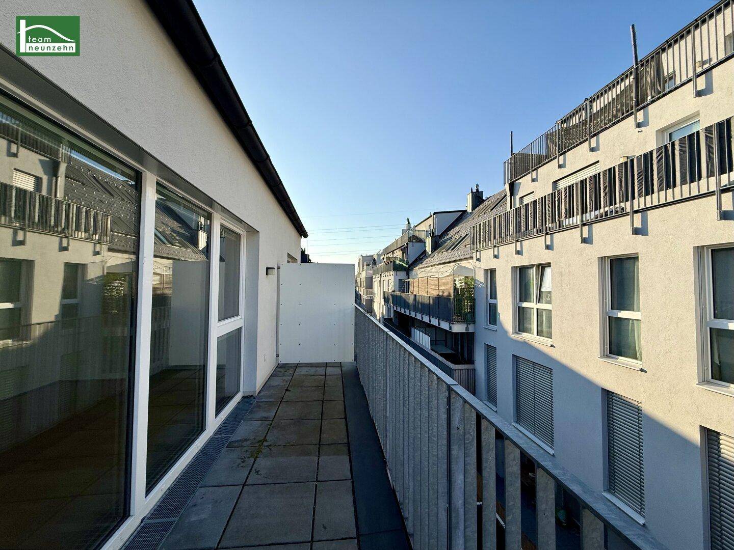 Langer Balkon mit Fliesenboden und Blick auf die umliegenden Gebäude.