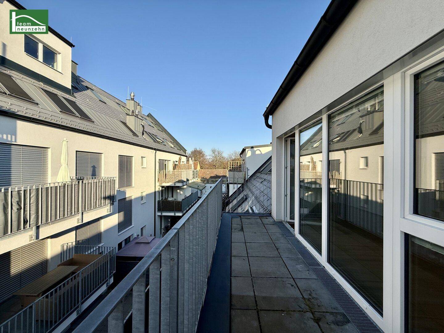 Langer Balkon mit Fliesenboden und Blick auf die umliegenden Wohngebäude.