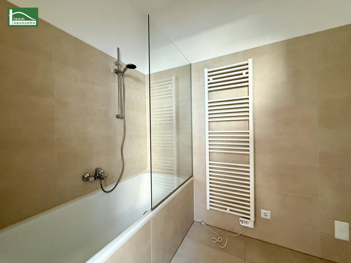 Badezimmer mit Badewanne, Duscharmatur und beheiztem Handtuchhalter.