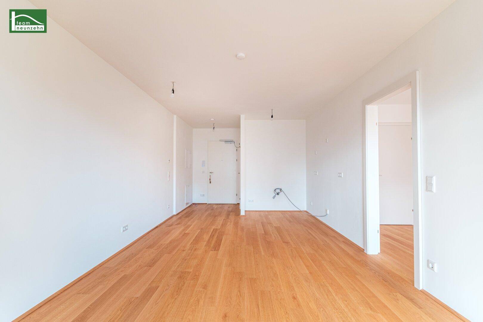 Heller Flur mit Parkettboden und mehreren Türen, der den Eingangsbereich des Apartments zeigt.