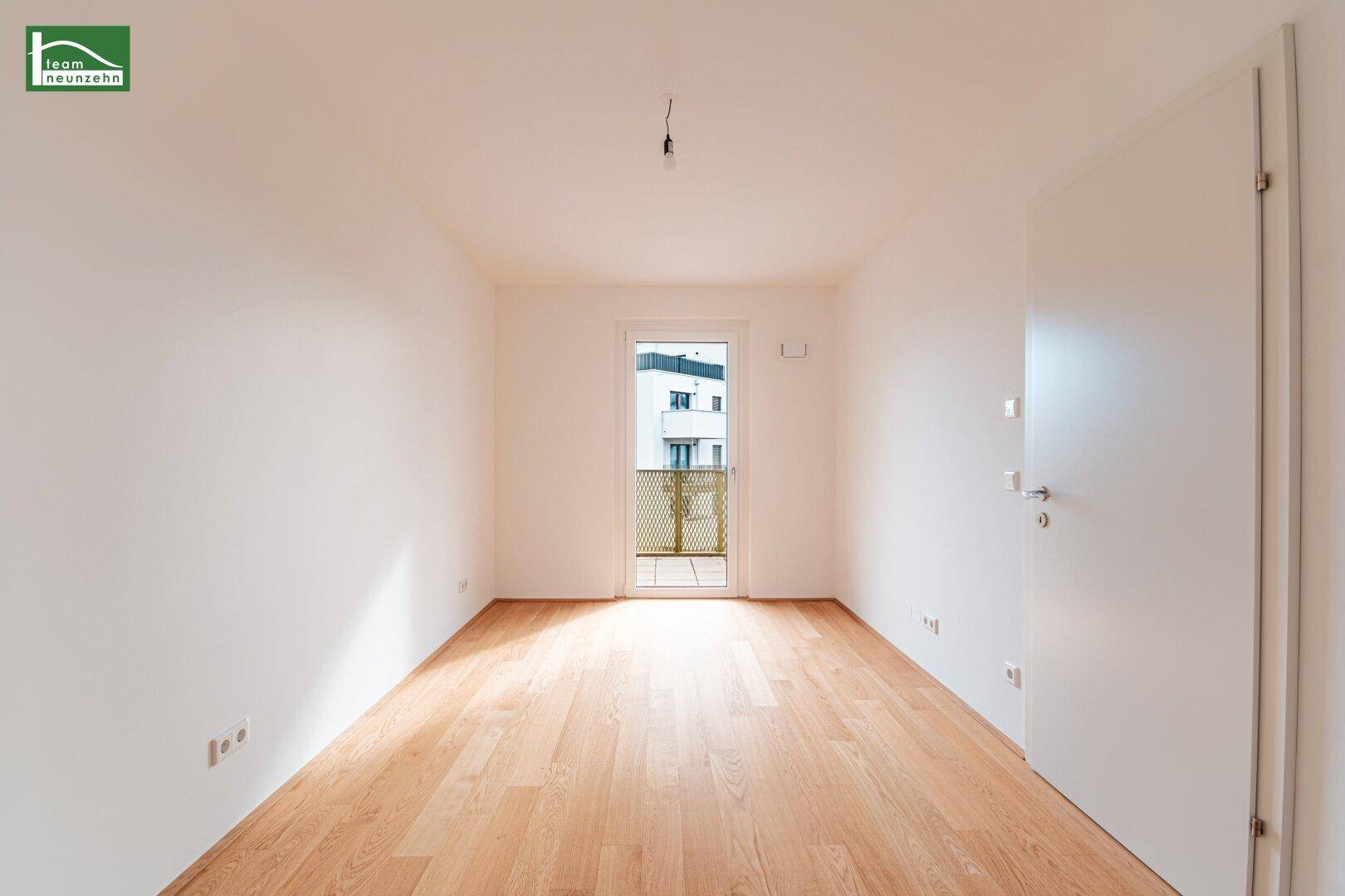 Leeres Zimmer mit Holzboden und Balkonzugang, ideal als Schlafzimmer oder Arbeitszimmer nutzbar.