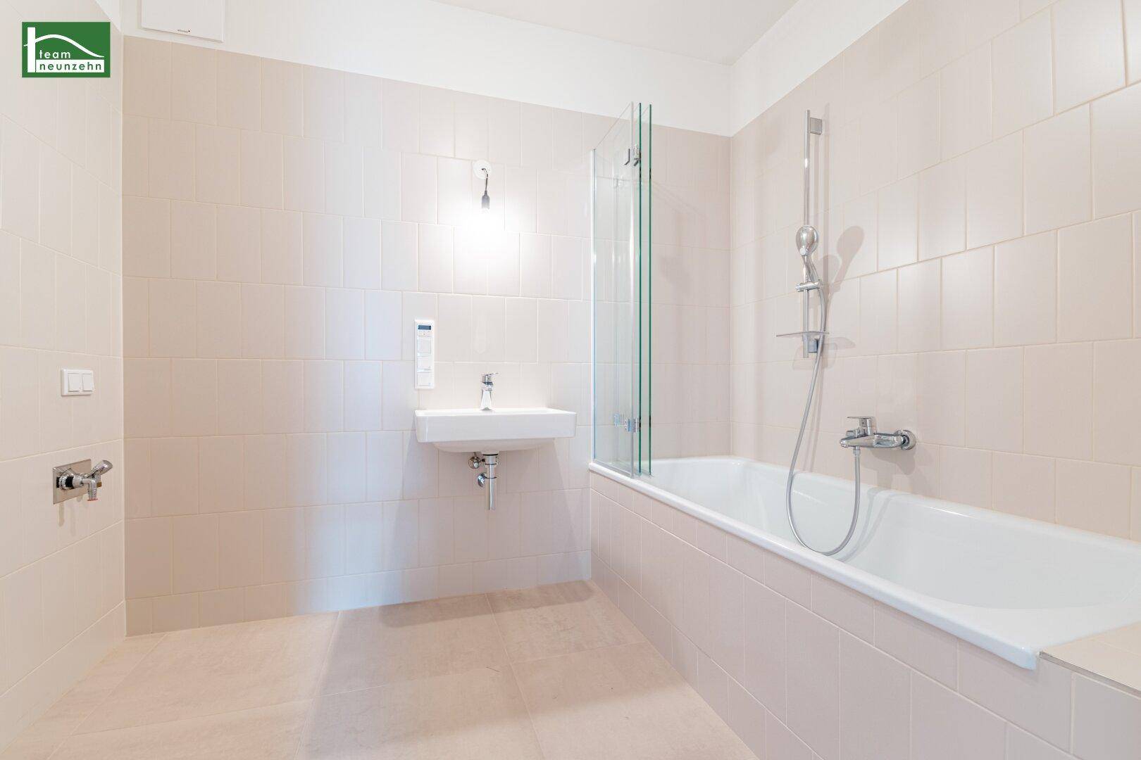 Modernes Badezimmer mit Badewanne, Duschabtrennung und hellem Fliesenboden.
