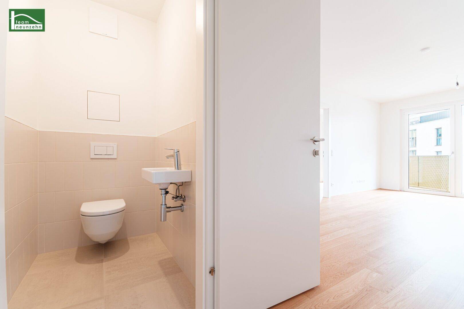 Separates Gäste-WC mit wandhängender Toilette und kleinem Waschbecken.