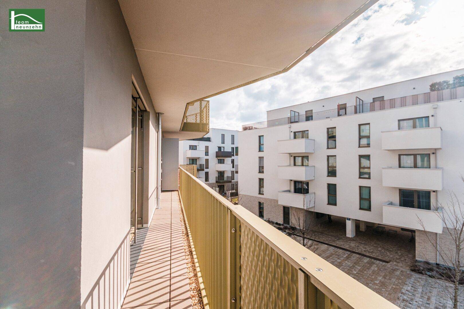 Langer Balkon mit Metallgeländer und Blick auf die umliegenden Gebäude und den Innenhof.
