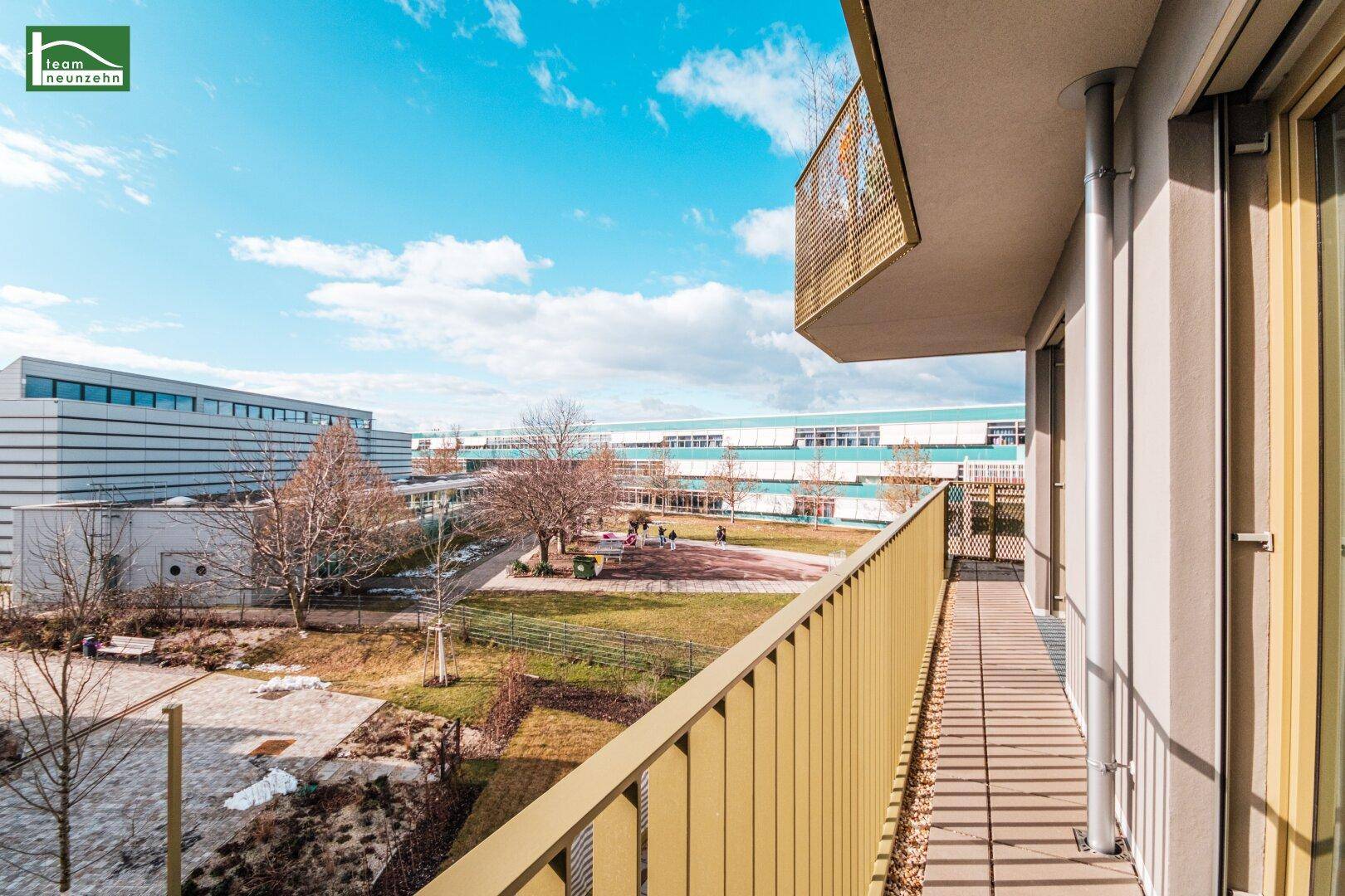 Langer Balkon mit Metallgeländer und Blick auf die grüne Umgebung.