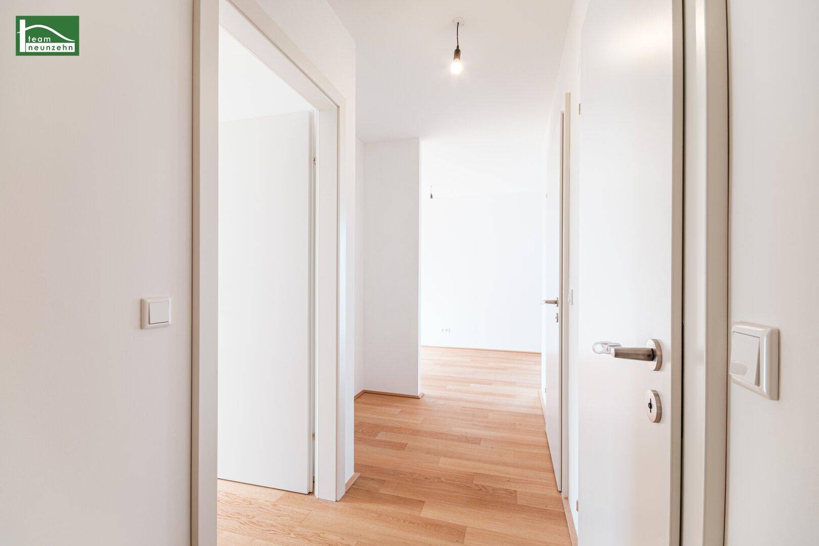Heller Flur mit Holzboden und mehreren Türen zu den angrenzenden Räumen.