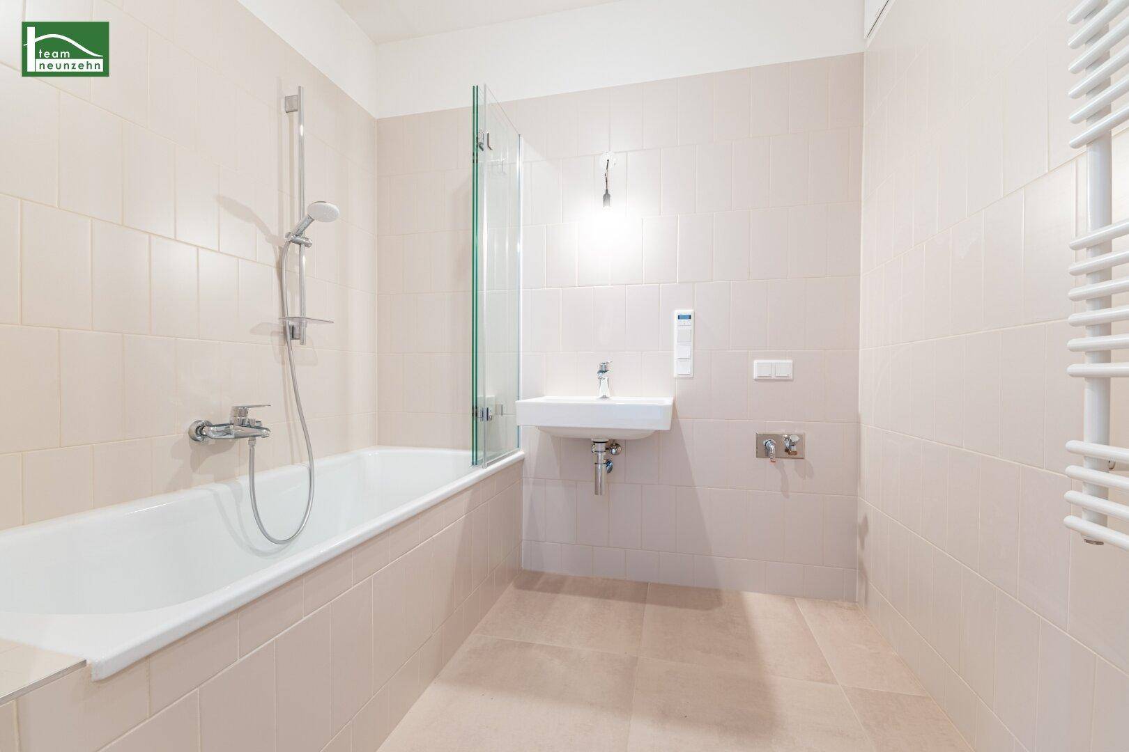 Modernes Badezimmer mit Badewanne, Waschbecken und beheiztem Handtuchhalter.