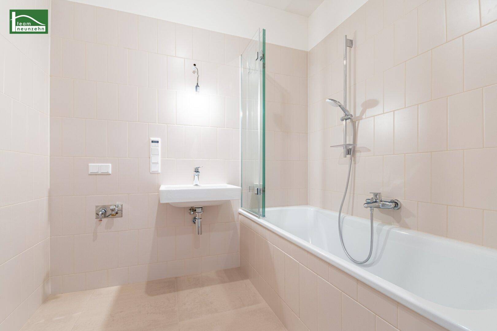 Modernes Badezimmer mit Badewanne, Waschbecken und hellen Fliesen.
