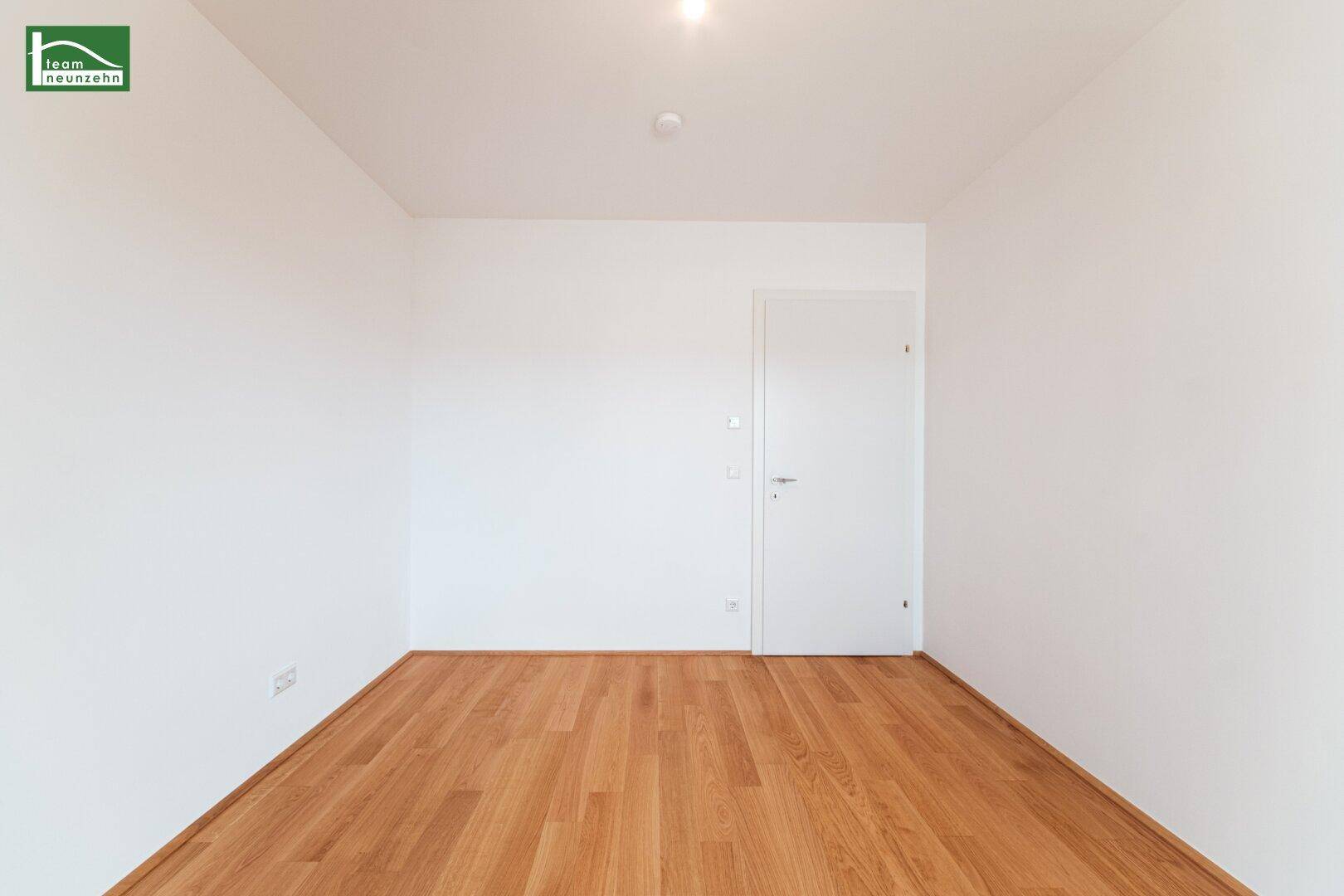 Heller, leerer Raum mit Holzboden und weiß gestrichenen Wänden, bereit zur individuellen Gestaltung.