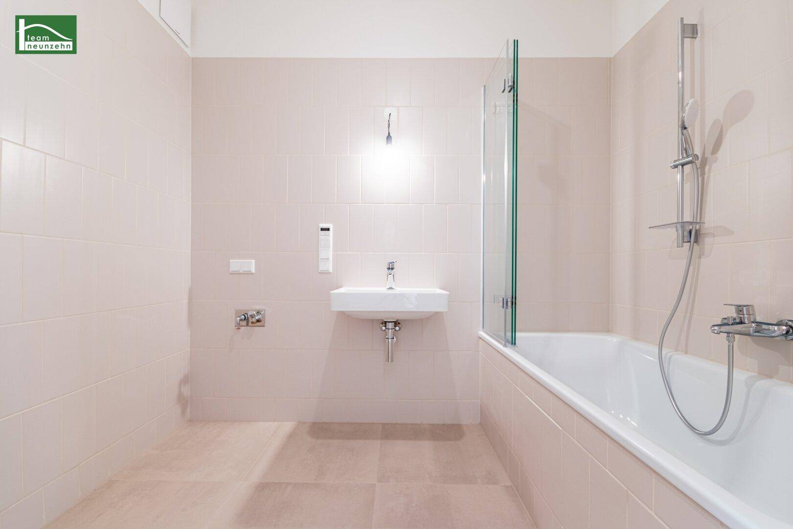 Modernes Badezimmer mit Badewanne, Waschbecken und hellen Fliesen.