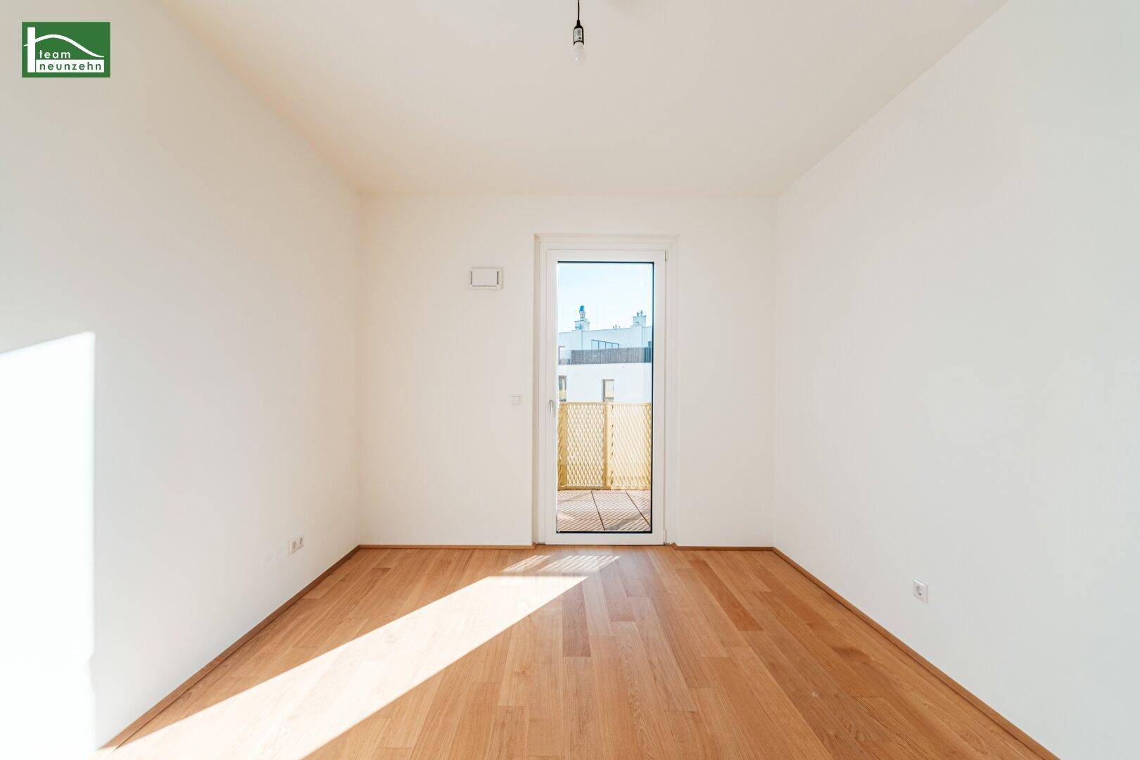 Helles, leeres Zimmer mit Parkettboden und Zugang zu einem privaten Außenbereich.