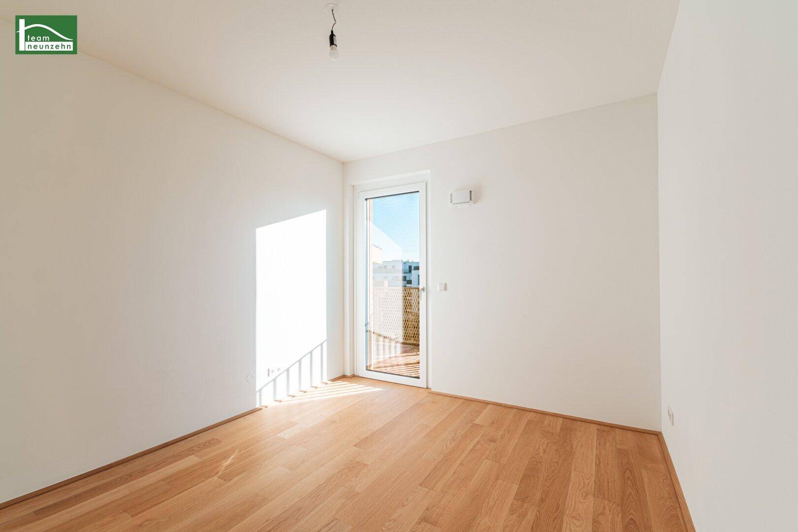 Sonniges Zimmer mit Parkettboden und direktem Zugang zu einem kleinen Balkon.
