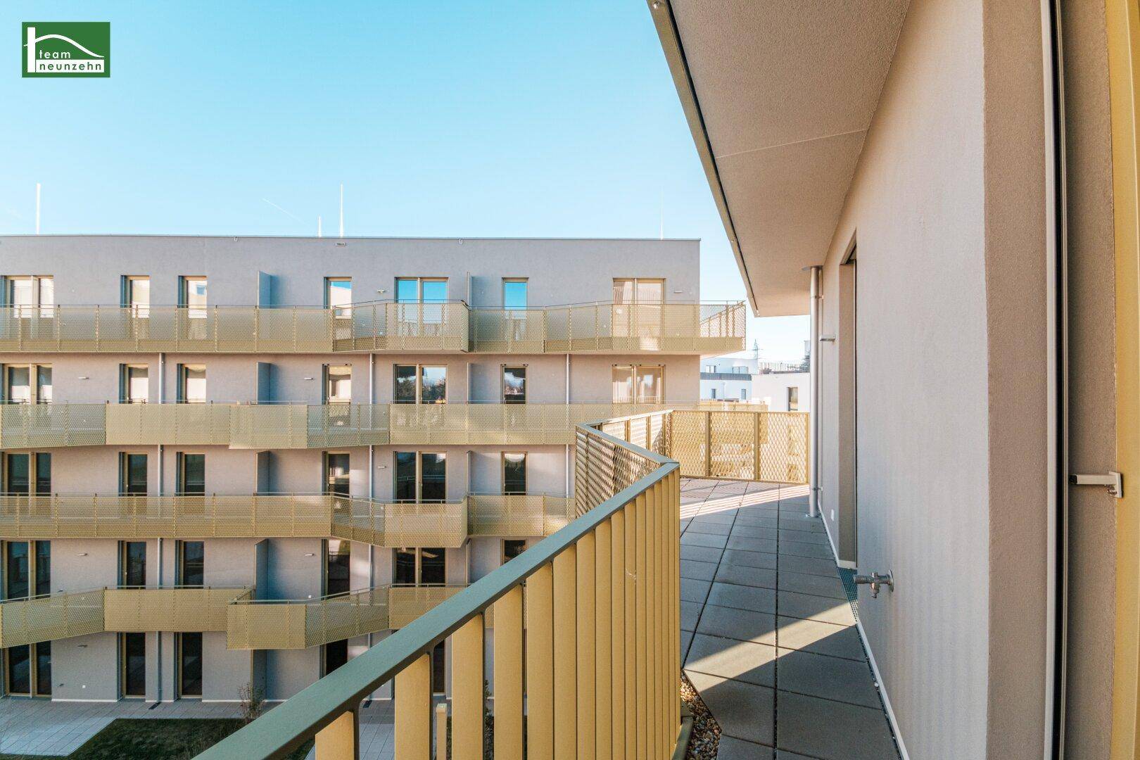 Sonniger Balkon mit moderner Architektur und Ausblick auf die Wohnanlage.