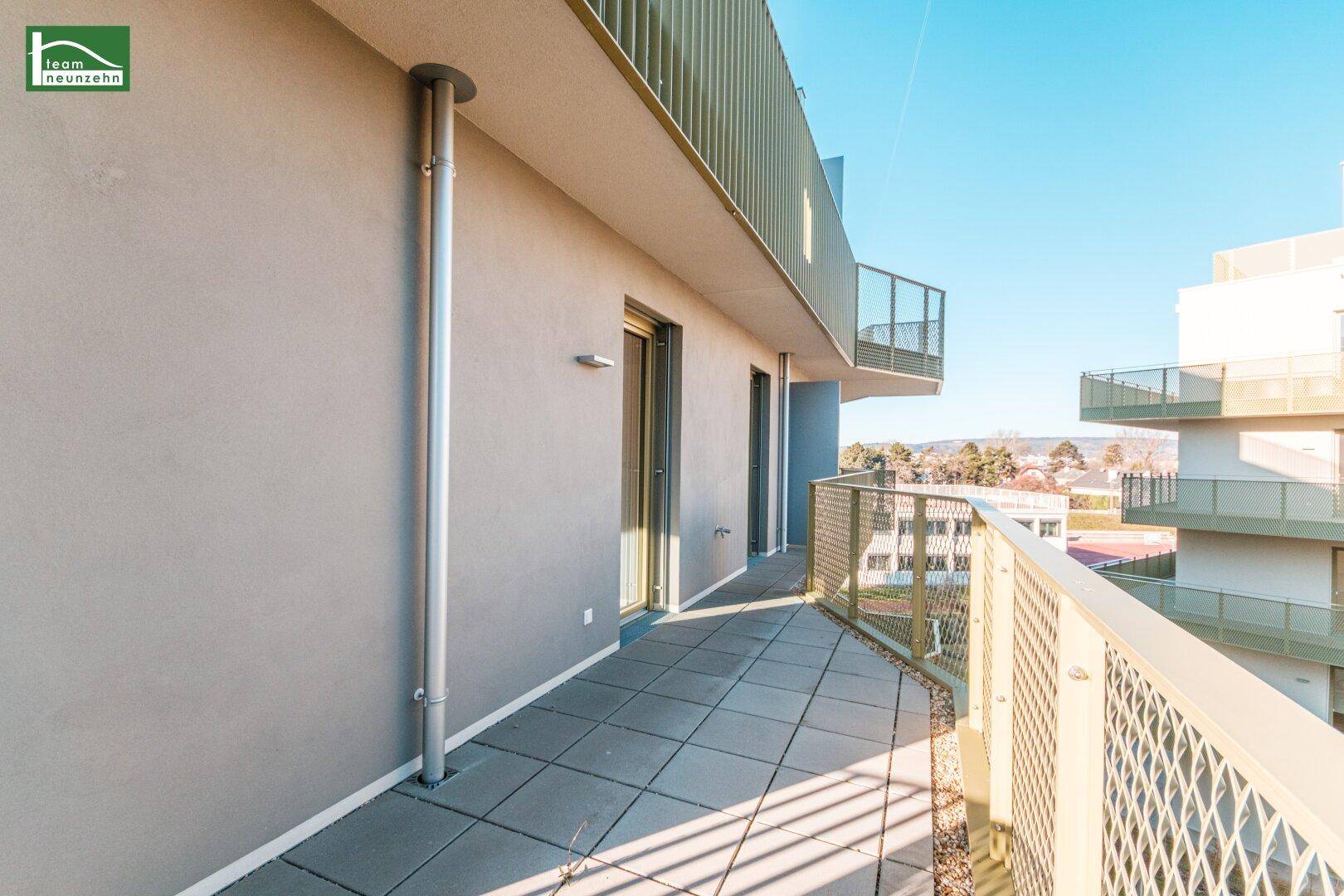 Geräumiger Balkon mit Fliesenboden und Blick auf die Nachbarschaft und Grünflächen.