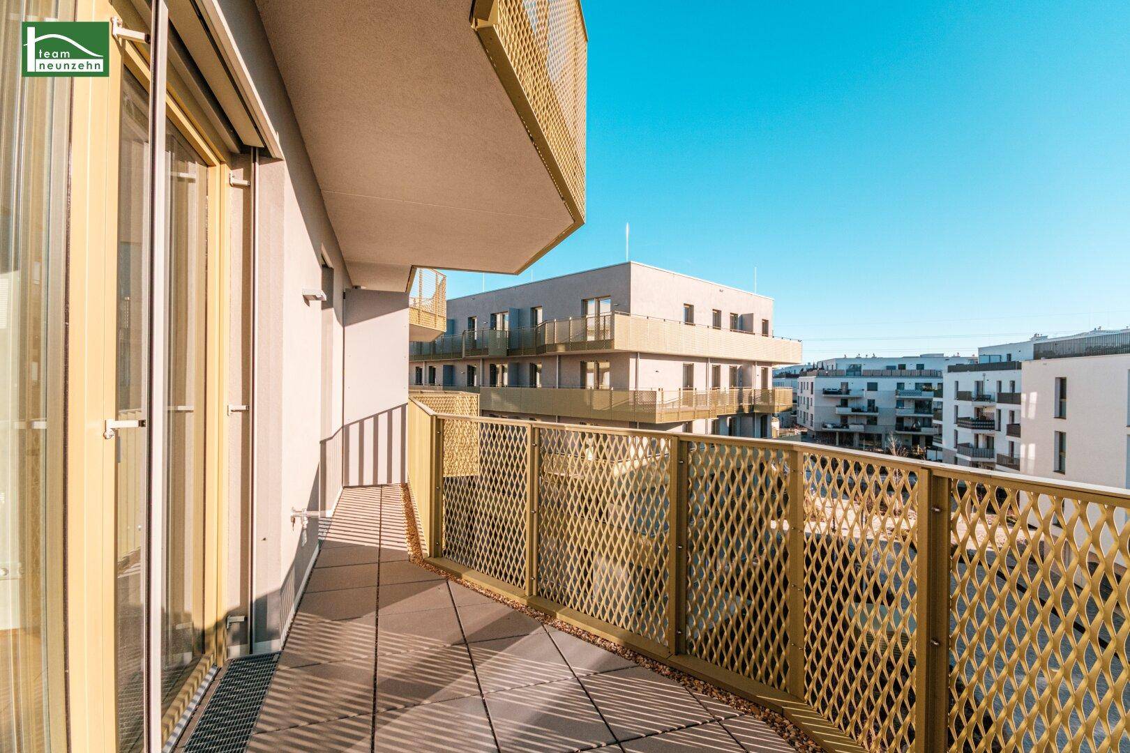 Balkon mit markantem goldenem Gittergeländer, Fliesenboden und Blick auf die Umgebung.
