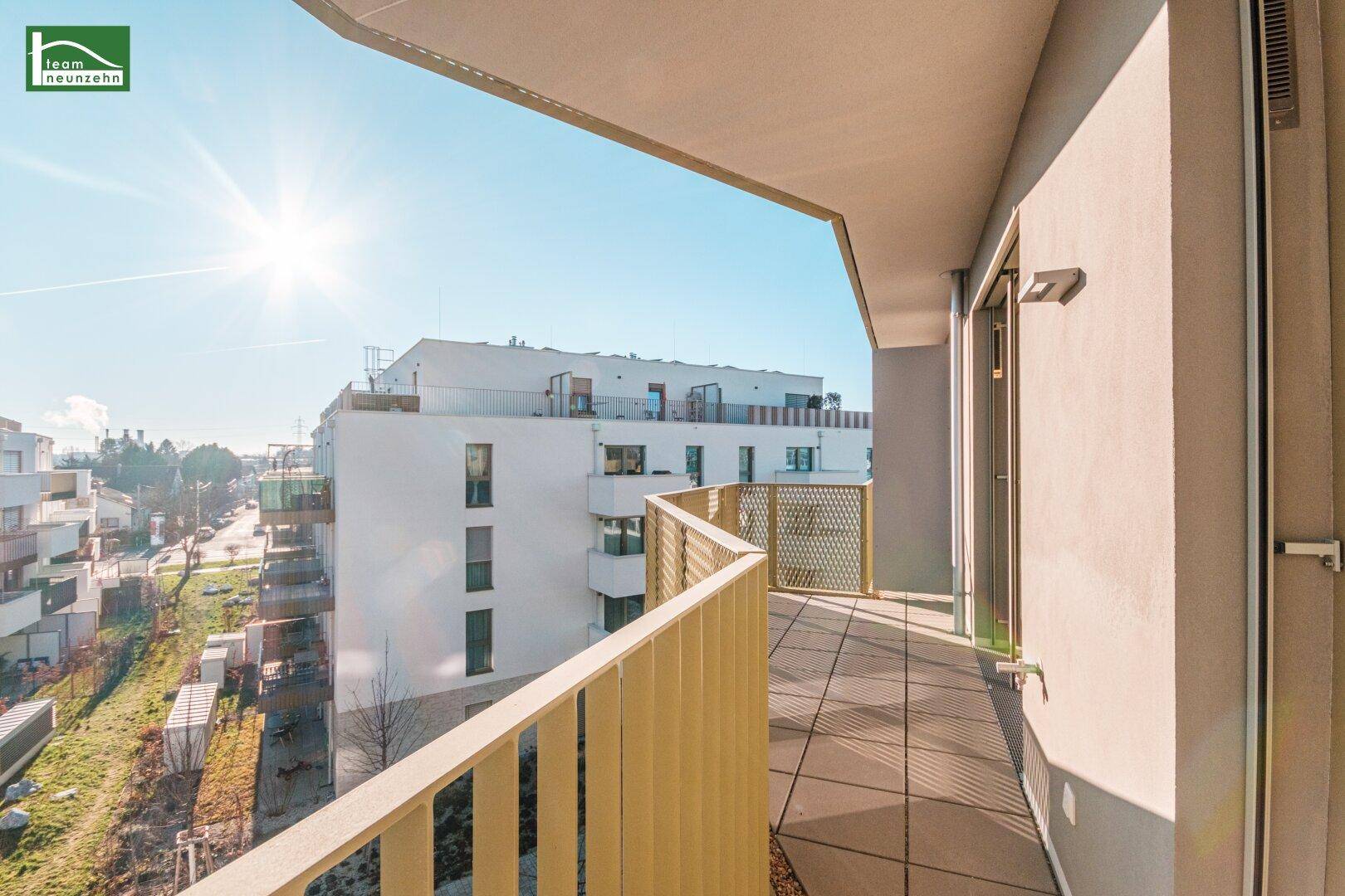 Sonniger Balkon mit Fliesenboden und modernem Geländer, bietet einen weiten Blick über die Umgebung.